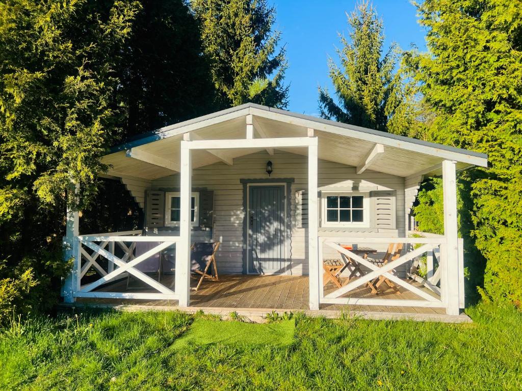 a white shed with a porch and a deck at Domki w Lesie in Silnowo