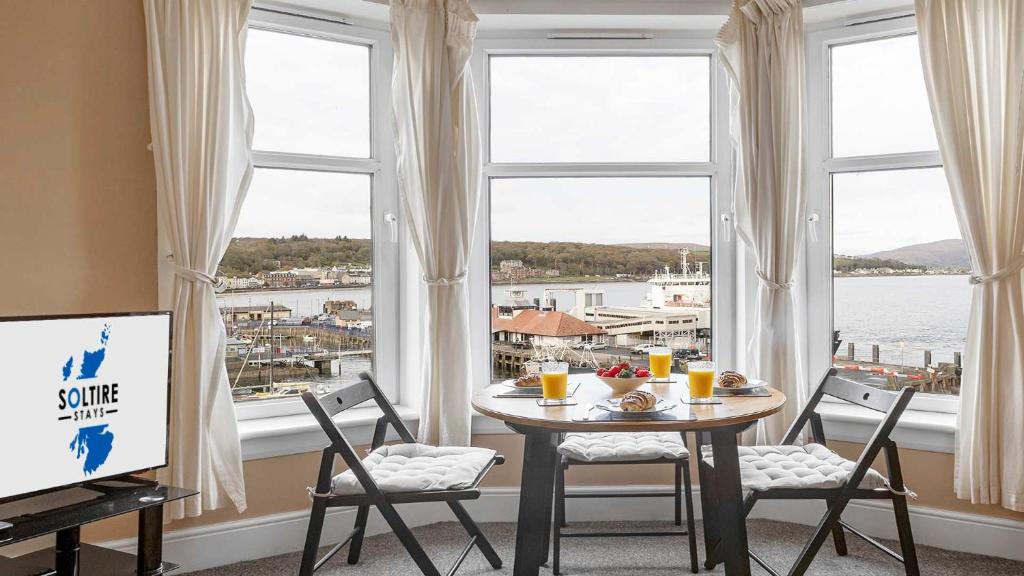a table and chairs in a room with a large window at Lady Mary Sea View in Rothesay