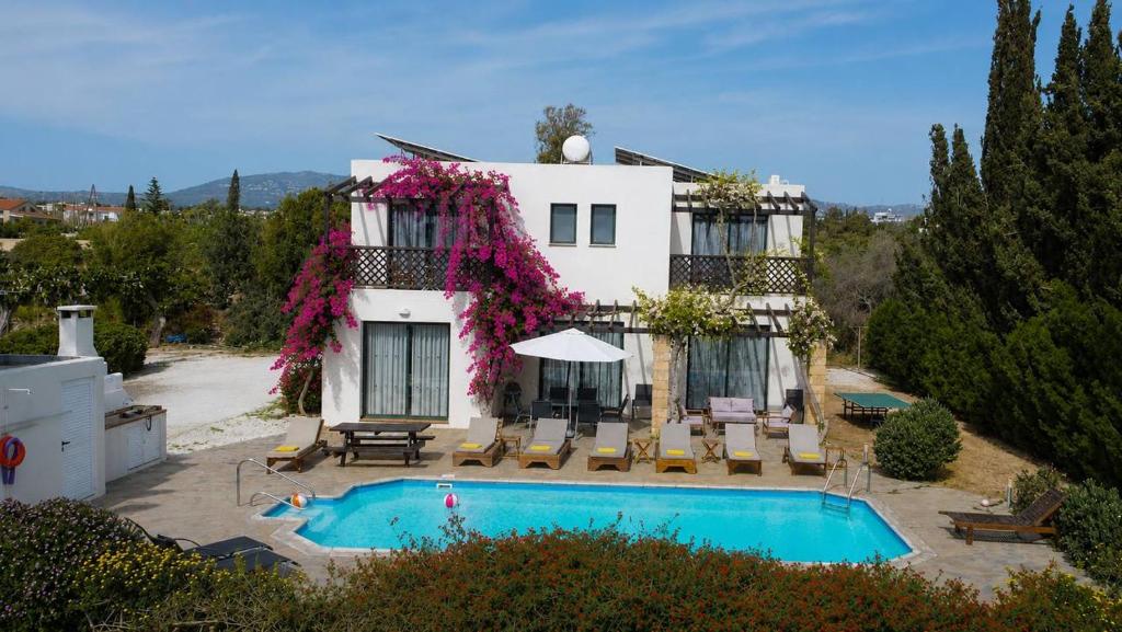 a house with a swimming pool in front of it at Banana Sunset Villas in Paphos