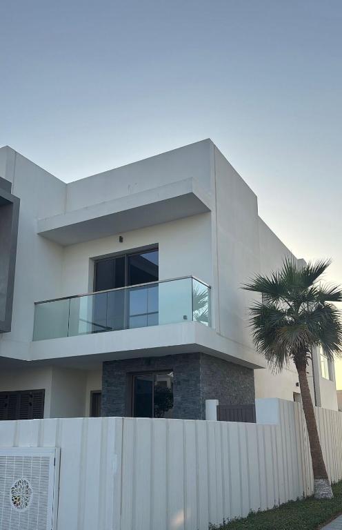 a white house with a palm tree in front of it at Home Sweet Home in Abu Dhabi