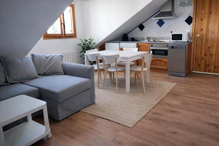 a living room with a couch and a table and a kitchen at Ibón de tebarray in Escarrilla