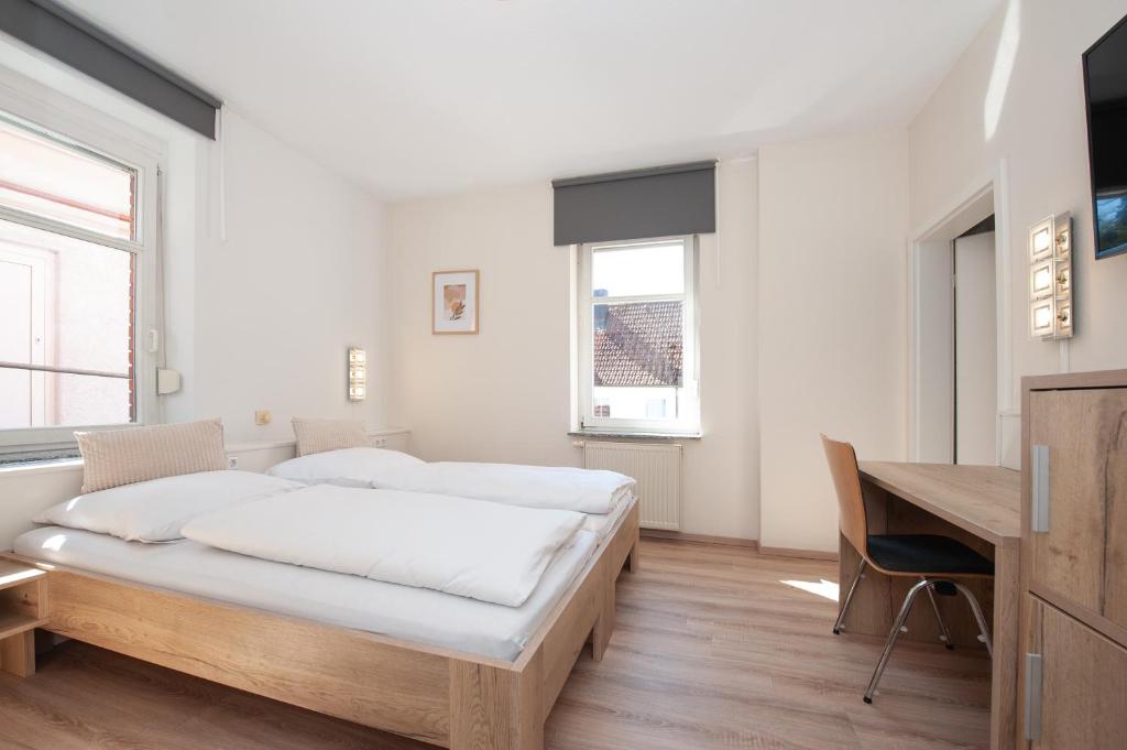 a white bedroom with a bed and a desk at Hotel Bären in Schramberg