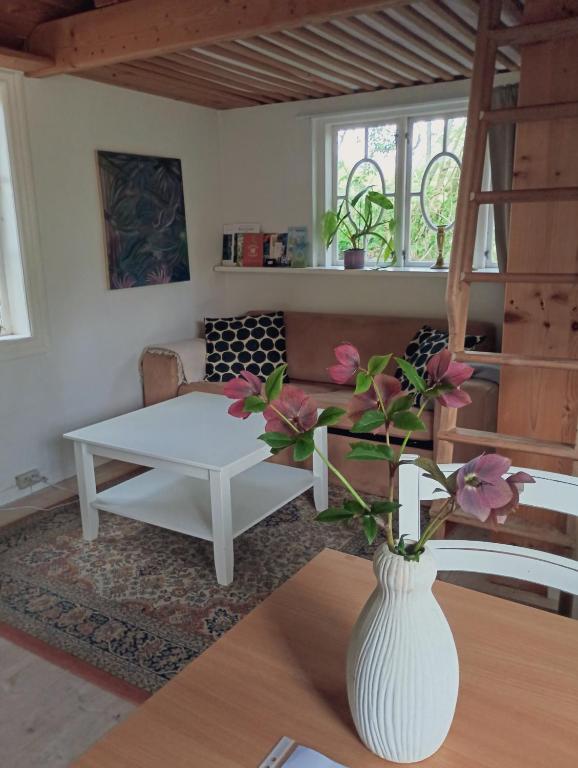 a living room with a white vase with flowers on a table at Cozy Cabin near Balka Beach with outdoor toilet and kitchen in Neksø