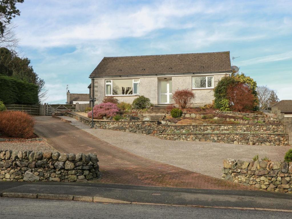 a house with a stone wall and a driveway at The Rowans in Newton Stewart