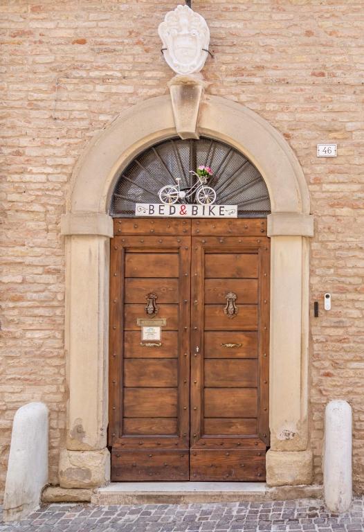 a large wooden door in a brick building at Antica Dimora Sforza Bed & Bike in Corinaldo