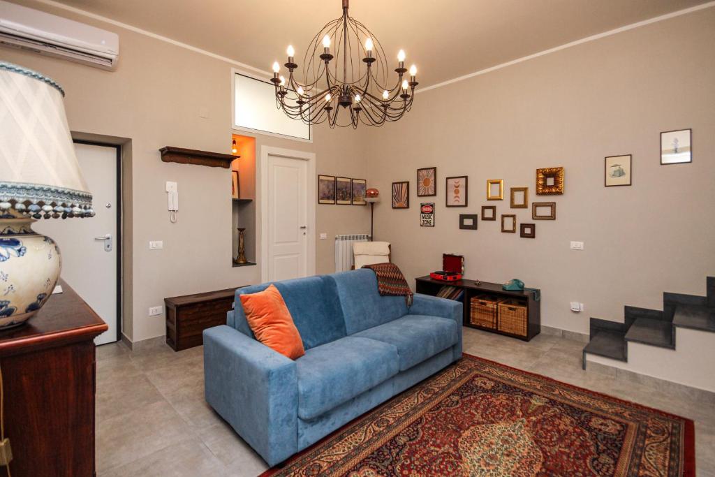 a living room with a blue couch and a chandelier at Appartamento Ferdinando - Relax & Style in Caserta
