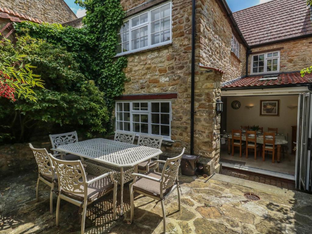 a patio with a table and chairs in front of a building at Crantock in Sherborne