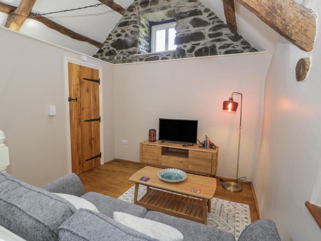 a living room with a couch and a tv at Beudy Bach in Llanbedr