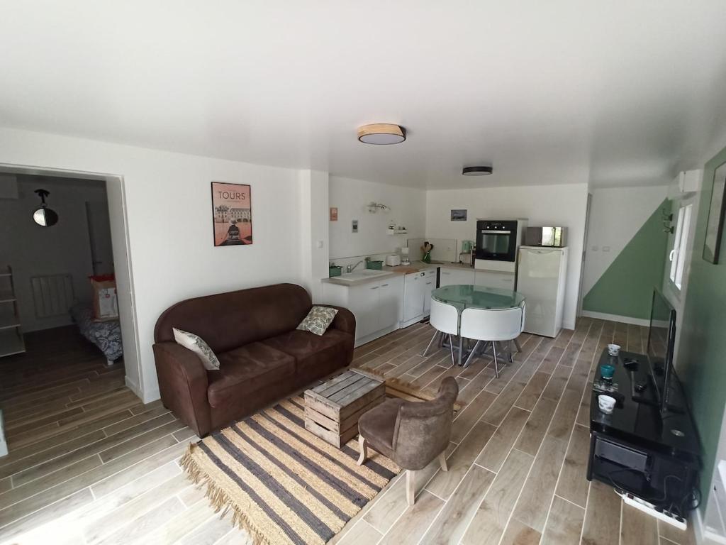 a living room with a couch and a kitchen at Le nid des mésanges in Veigné