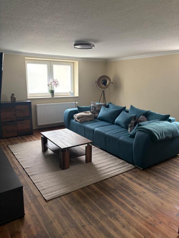 a living room with a blue couch and a table at FeWo Johann Friedrich in Hilpoltstein