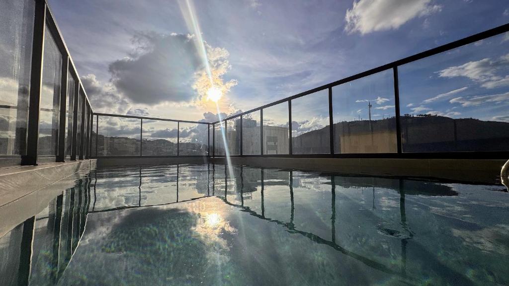 a swimming pool with the sun shining on the sky at Suporte VIP: TOPstudio no Centro c/Piscina Jacuzzi in Poços de Caldas