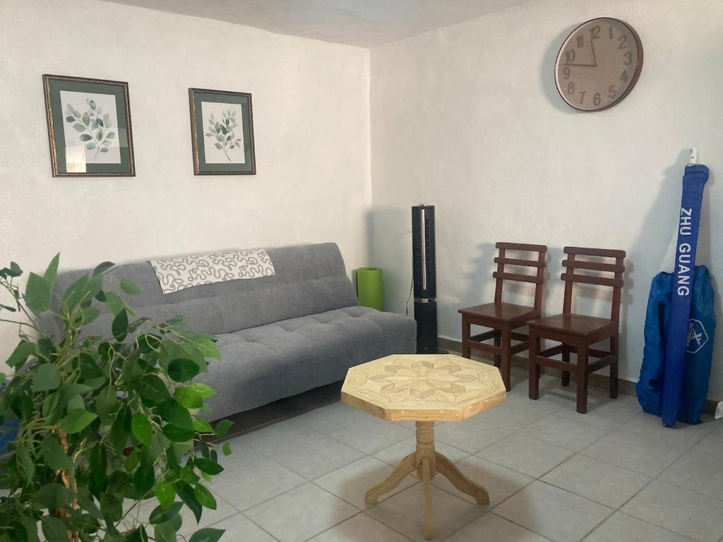 a living room with a couch and a clock on the wall at Casa Cangrejos in Cabo San Lucas