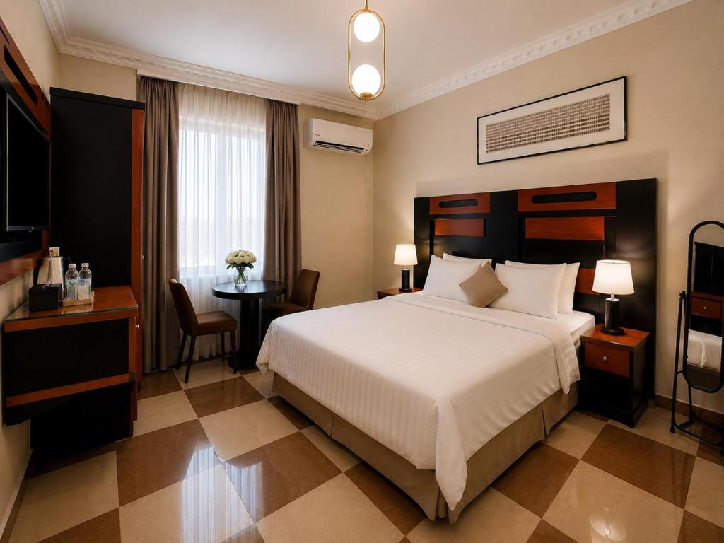 a hotel room with a bed and a desk and a window at شقق عناوين الفخامة in Şāmitah