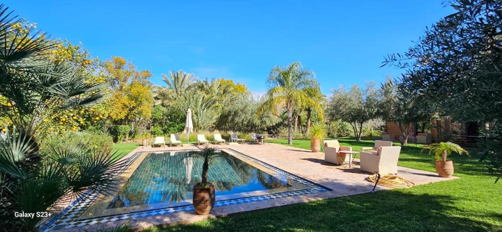 a swimming pool in a yard with chairs and trees at Belle villa avec piscine privée in Ala el Ma
