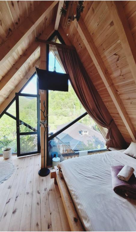 a bedroom with a bed and a large window at SkyFrame cottage with pool in Plav
