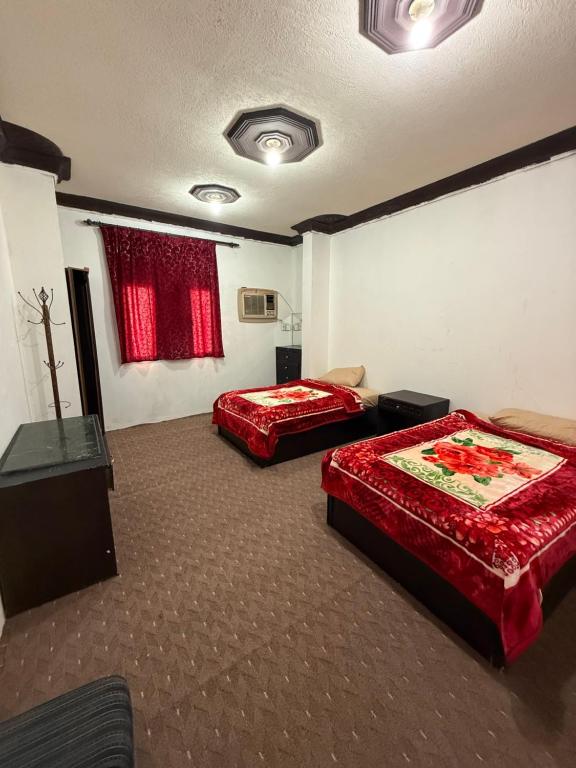 two beds in a room with red sheets at شقق مفروشة العزيزية in Hail