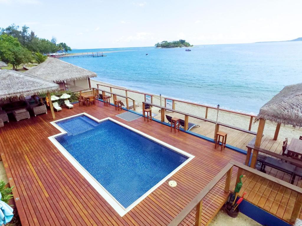 a deck with a swimming pool on the beach at Vanuatu Beachfront Apartments in Port Vila
