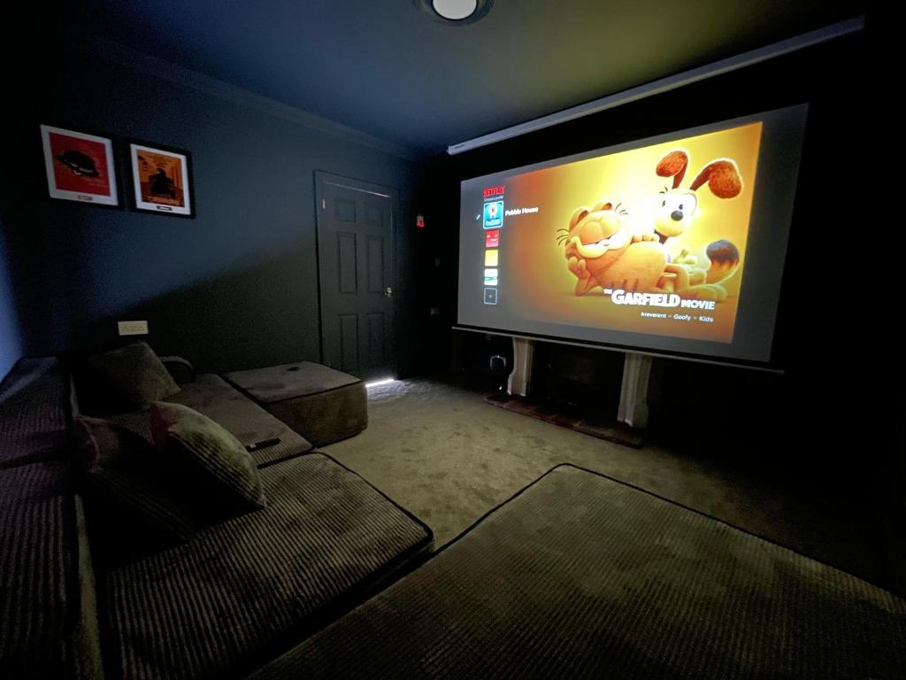 a living room with a large tv in a dark room at Sheringham Luxury, Cinema, Hot Tub & Beach in Sheringham
