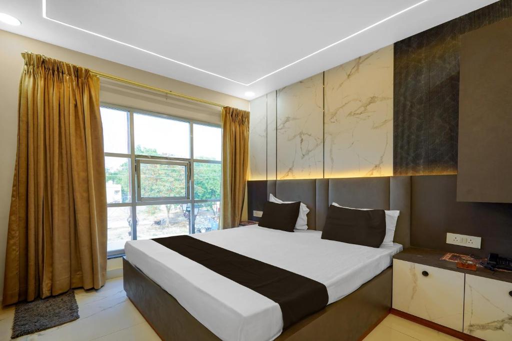 a bedroom with a large bed and a window at Super Hotel O RS PALACE in Jhānsi