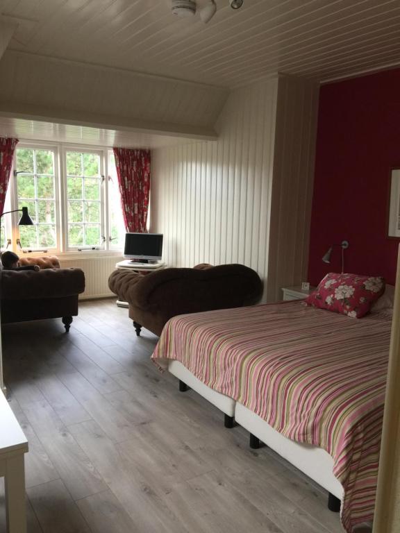 a bedroom with two beds and a couch and a television at Villa Hoog Duin in Domburg