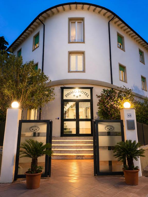 a white building with two potted plants in front of it at Primo Hotel in Marciana Marina