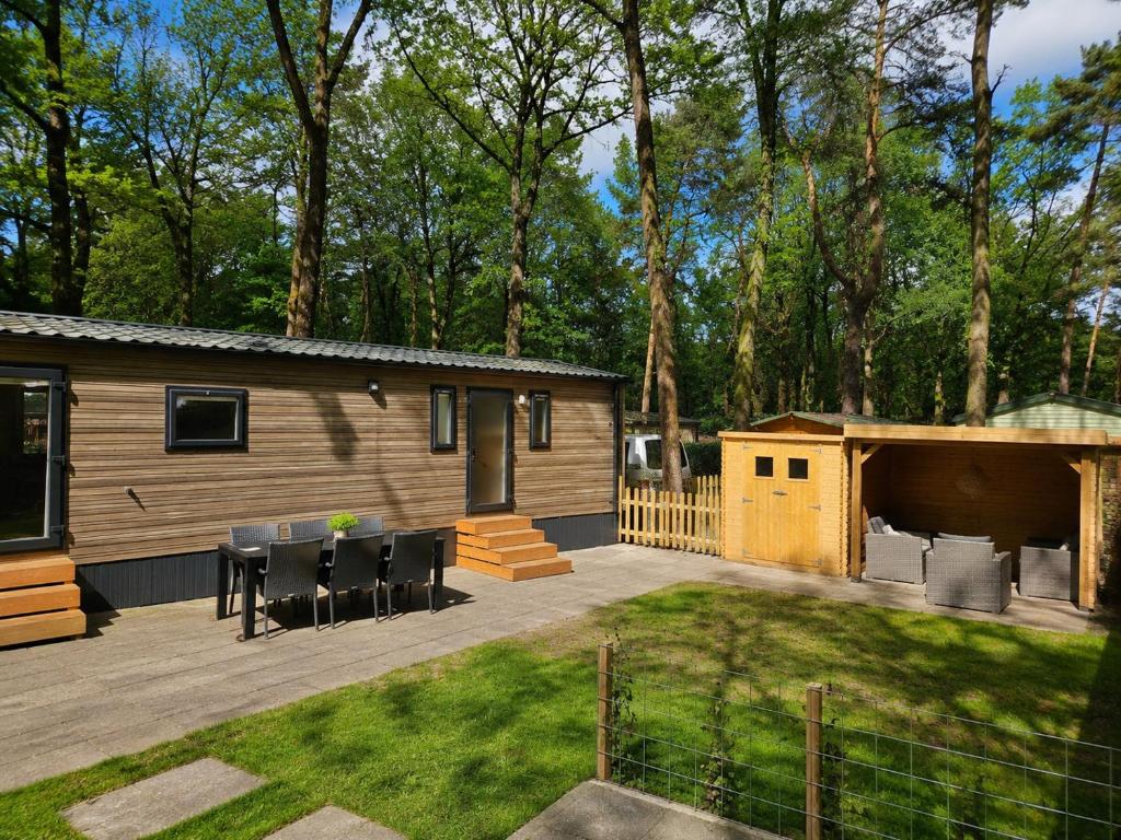 ein Hinterhof mit einer Hütte mit Tisch und Stühlen in der Unterkunft Roosje in Hoenderloo