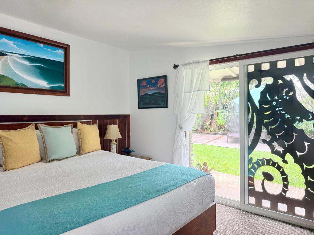 a bedroom with a bed and a sliding glass door at Kalani Hawaii Private Lodging in Pupukea