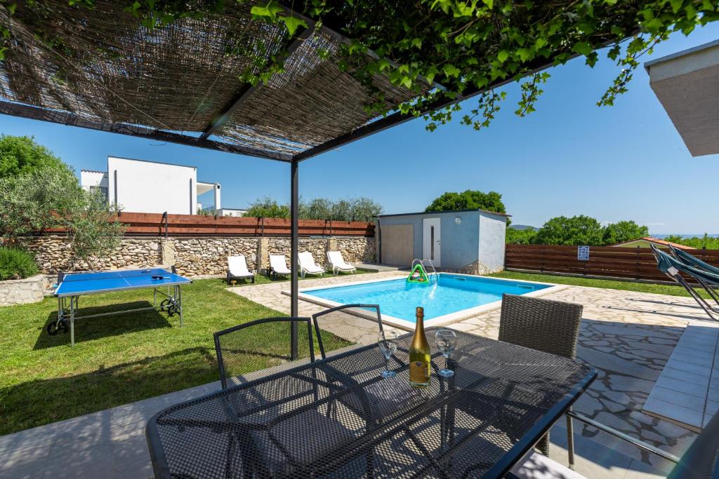 a backyard with a pool and a table and chairs at Holiday Home Casa Vida in Rakalj