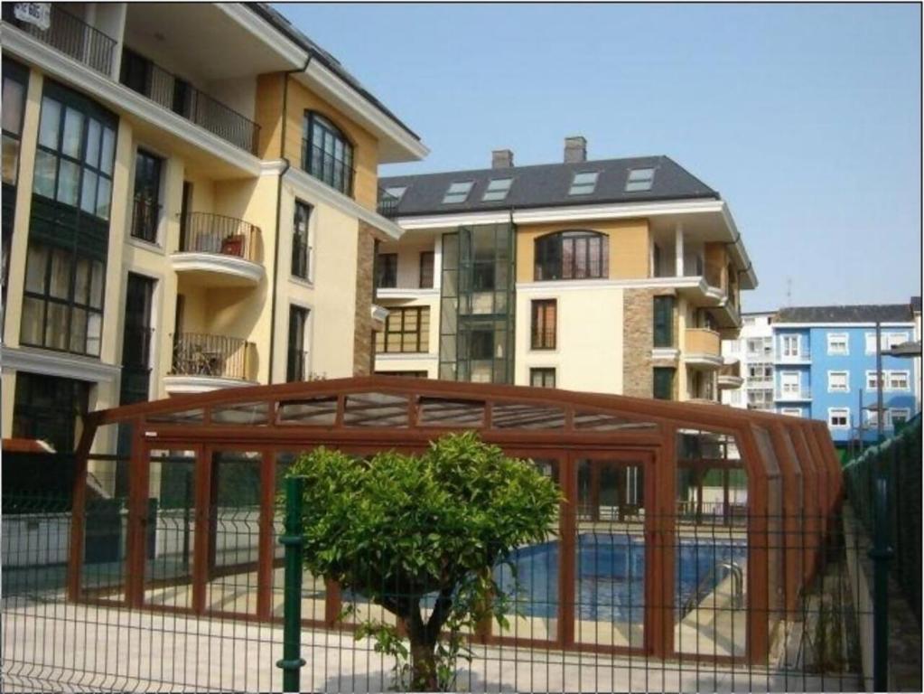 a fence in front of a building with a tree at Duplex Playa Rapadoira con piscina in Foz