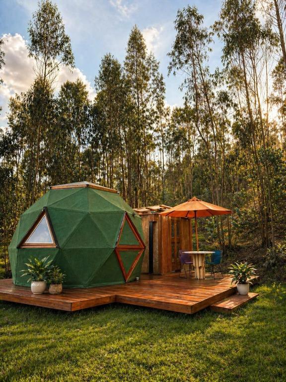 a green tent on a deck with a table and an umbrella at Glamping mágico en el Bosque in Oicatá