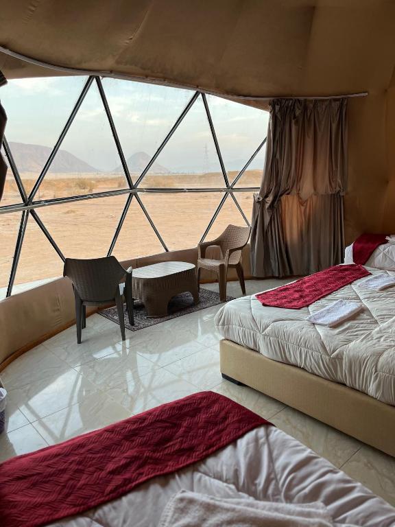 a bedroom with two beds and a view of the desert at FLORA RUM LUXURY CAMP & Bubble Hotel in Wadi Rum