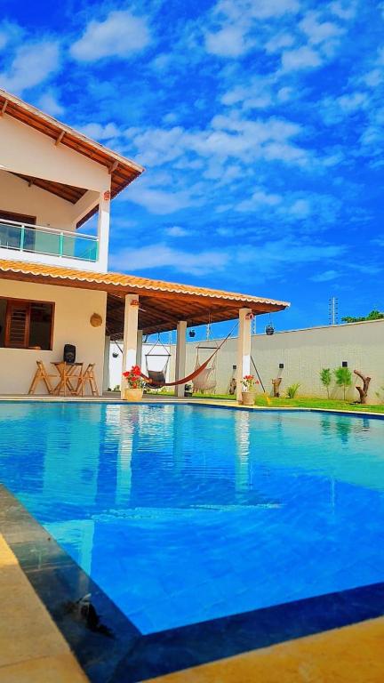 a large blue swimming pool in front of a house at Casapraiatracuá in Beberibe