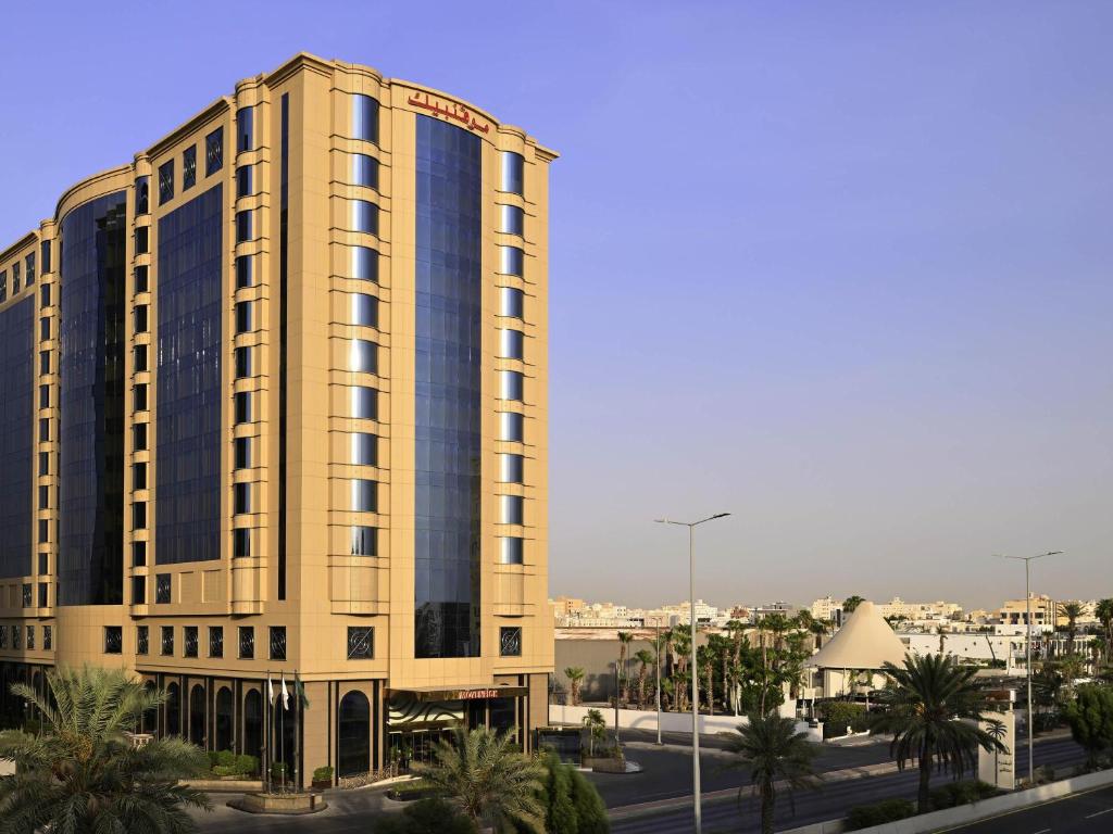 a tall yellow building with a lot of windows at Mövenpick Hotel City Star Jeddah in Jeddah