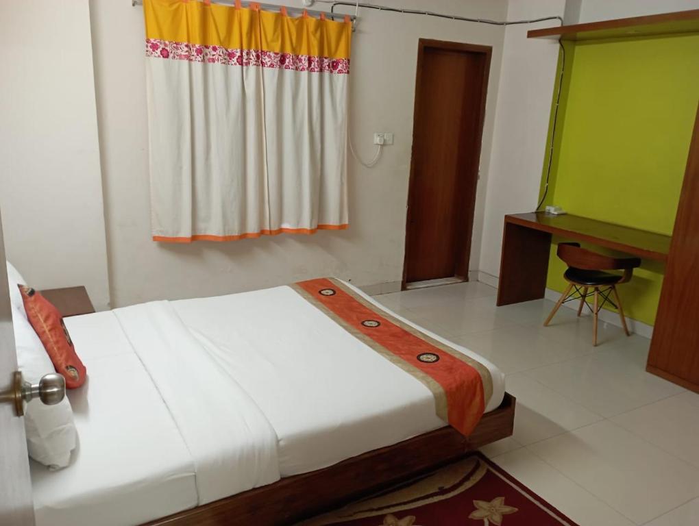 a bedroom with a bed and a desk and a window at The Green Hotel in Maheshkhāli