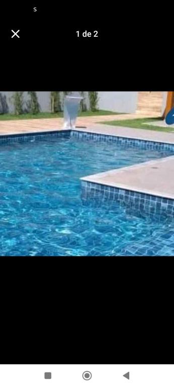 a swimming pool with blue water and a fountain at Nosso lar hostel in Cuiabá