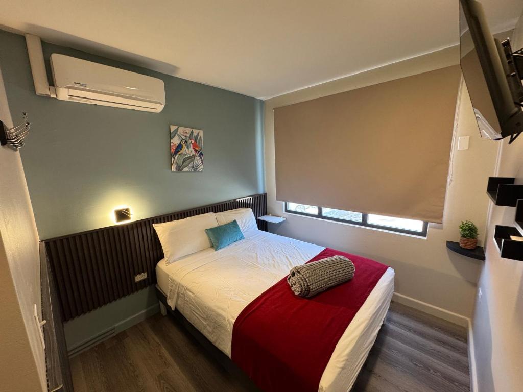 ein kleines Schlafzimmer mit einem Bett und einem Fenster in der Unterkunft Central Boutique Hotel in Oranjestad