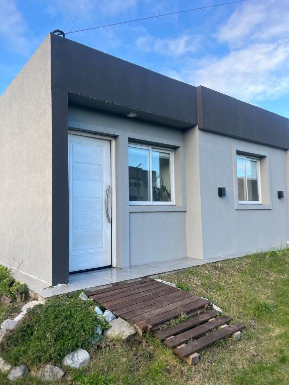 a house with a white door and a wooden stairs at Refugios del Parque in Necochea