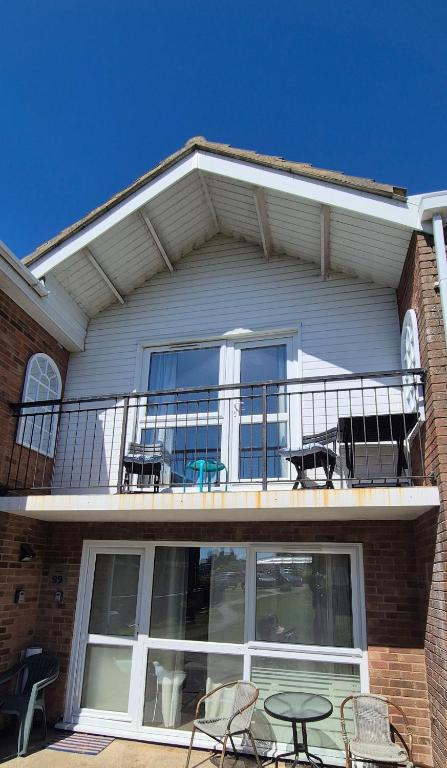 a house with a balcony with chairs and a table at The cosy house in Corton