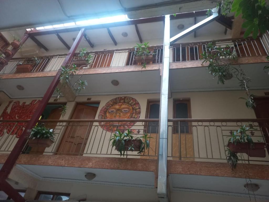 a building with a balcony with potted plants on it at Hostal Inca in Sucre