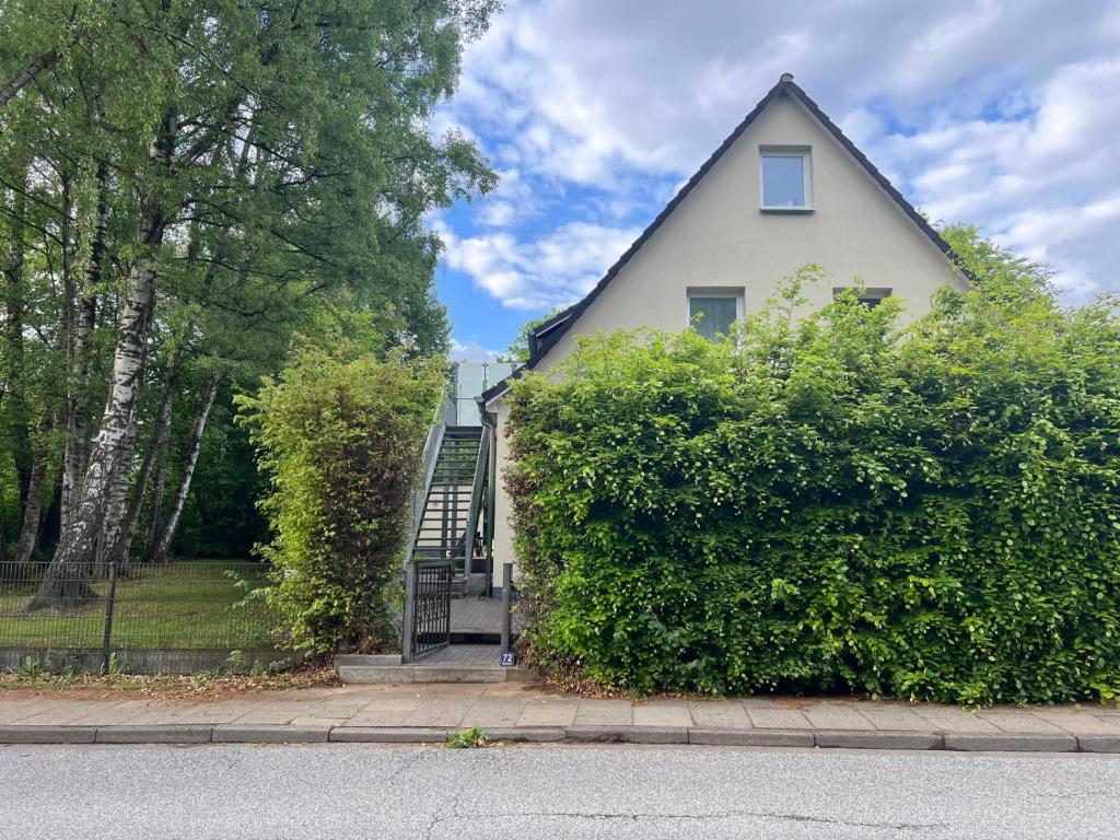 a white house with a staircase behind a hedge at Premium Apart Villa Hamburg in Hamburg