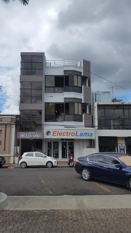 two cars parked in front of a building at Hotel Libano in San Francisco de Macorís
