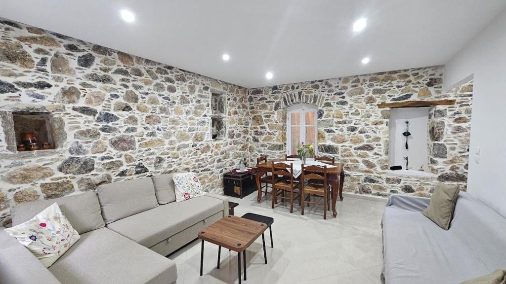 a living room with a couch and a stone wall at Summerstone Cottage in Aliveri