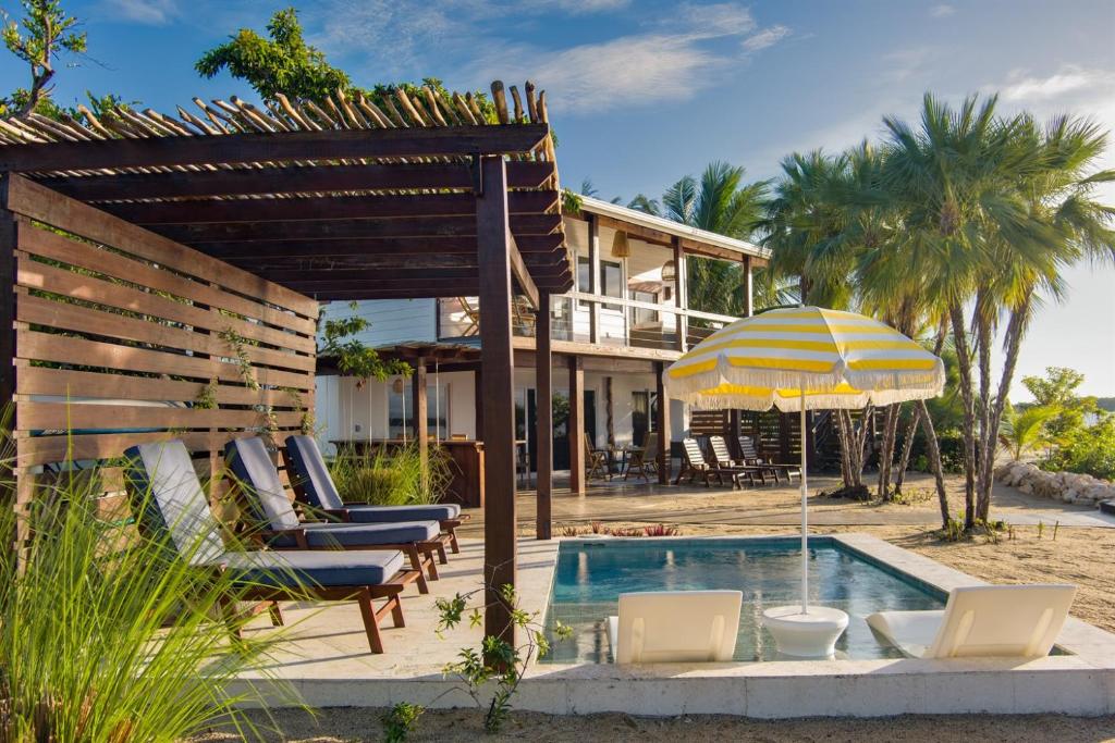 a pool with chairs and an umbrella next to a house at Luxury Waterfront 3bd Villa w Pool Dock in Maya Beach