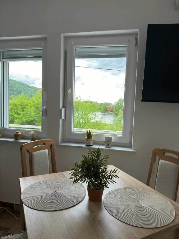a dining room with a table and two windows at Apartman Riverside Ripač in Ripač