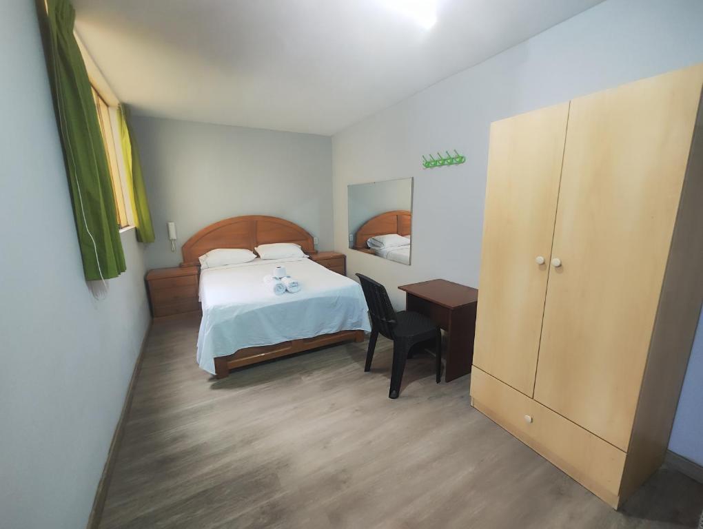 a bedroom with a bed and a desk with a chair at Hostal Romances in Chimbote