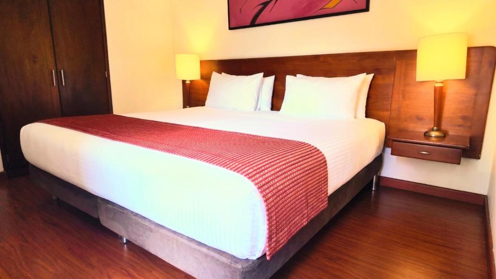 a large bed in a hotel room with two lamps at Hotel American Blessing in Bogotá