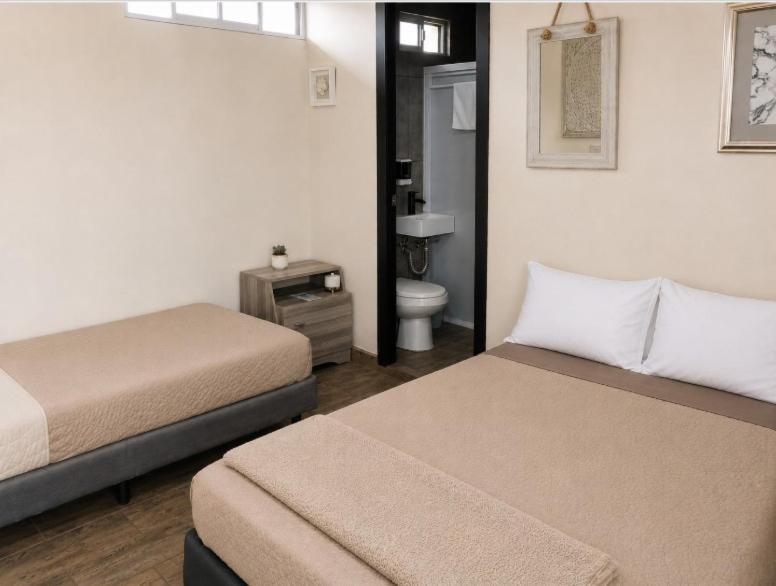 a bedroom with two beds and a bathroom with a toilet at Dalia Room, Paseo Durango in Durango