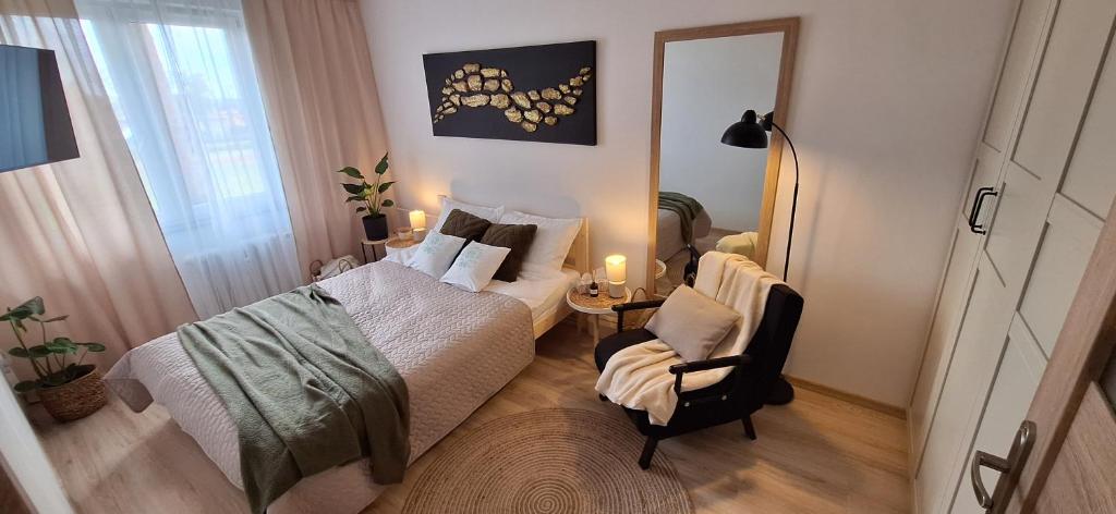a bedroom with a bed and a chair and a mirror at Zielone Okno Apartament w Augustowie blisko jeziora i centrum in Augustów
