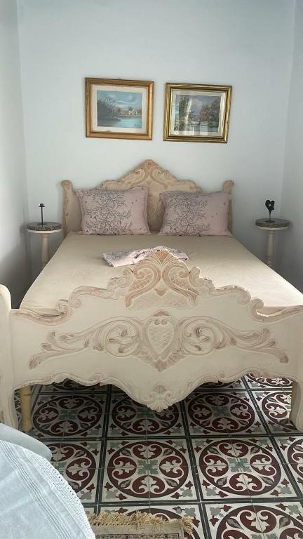 a bedroom with a large bed with two pictures on the wall at Beit Emna2 in Kairouan
