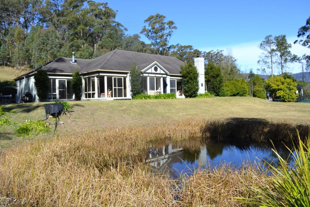 una casa con un estanque delante de ella en Clerevale Vacation Home en Kangaroo Valley